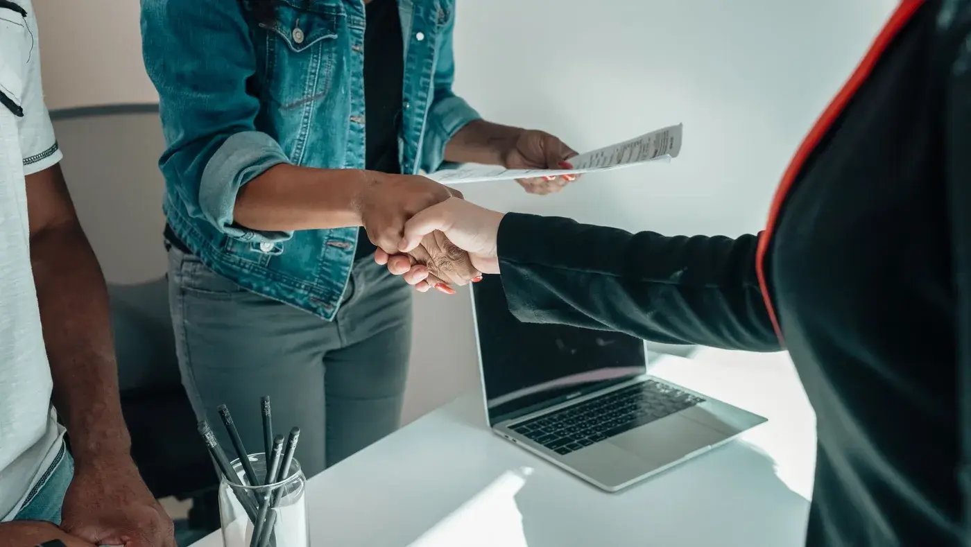 Two people shaking hands across an office desk